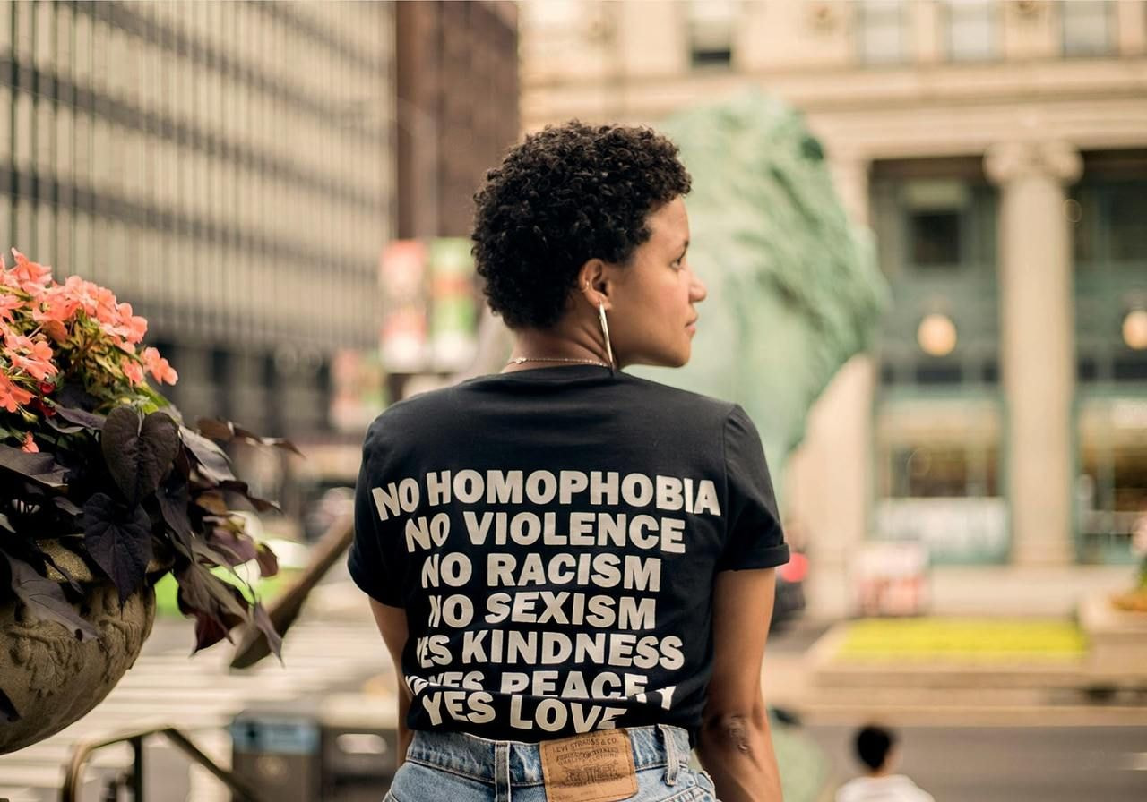A woman is wearing a black t-shirt with a statement text print on the back.
