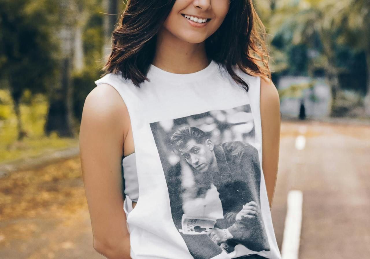 A woman wearing a white tank top with a photo print on the front.