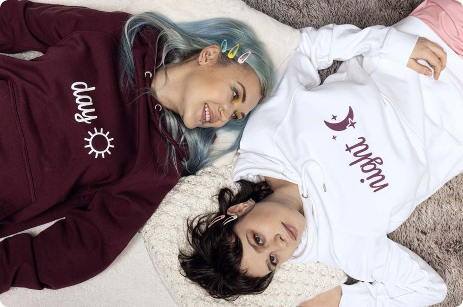 photo of two women laying next to each other wearing day and night couple's hoodies