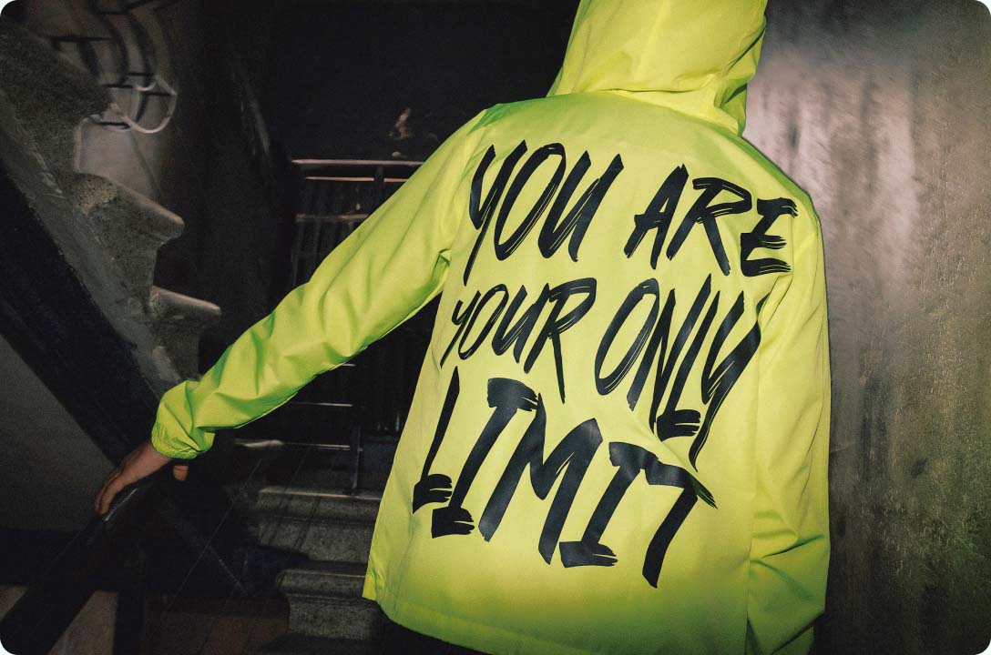 eine Person, die eine gelbe Jacke mit schwarzer Aufschrift (Print on Demand Produkte) trägt